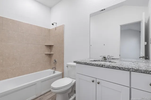 a bathroom with a granite countertop sink toilet and shower