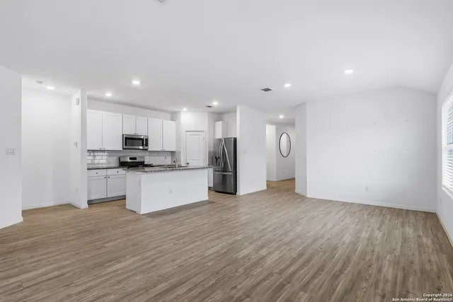 a view of kitchen with granite countertop stainless steel appliances refrigerator sink and cabinets