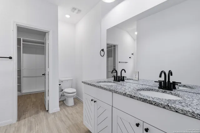 a bathroom with a granite countertop sink a toilet and a mirror