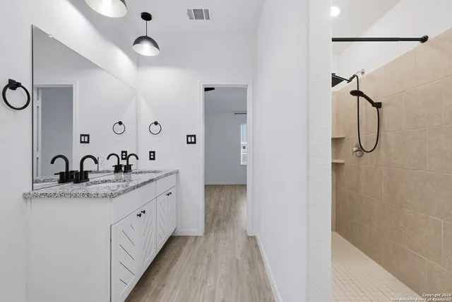 a bathroom with a granite countertop sink a mirror and shower