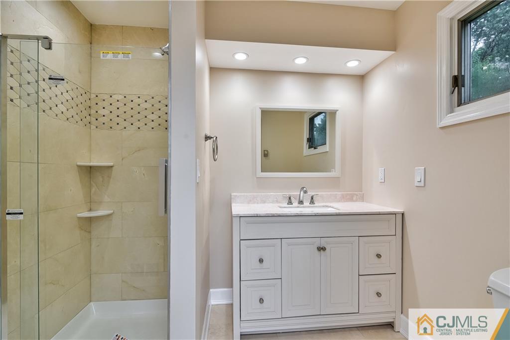 113 Stony Road Edison, NJ 08817 - Photo 16 of 20 a bathroom with a granite countertop sink a mirror a shower and a bathtub