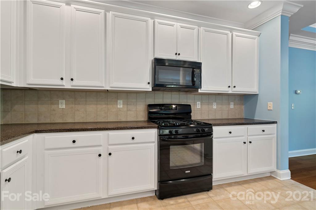 8929 Rosalyn Glen Road, Unit 108 Cornelius, NC 28031 - Photo 12 of 28 a kitchen with white cabinets and appliances