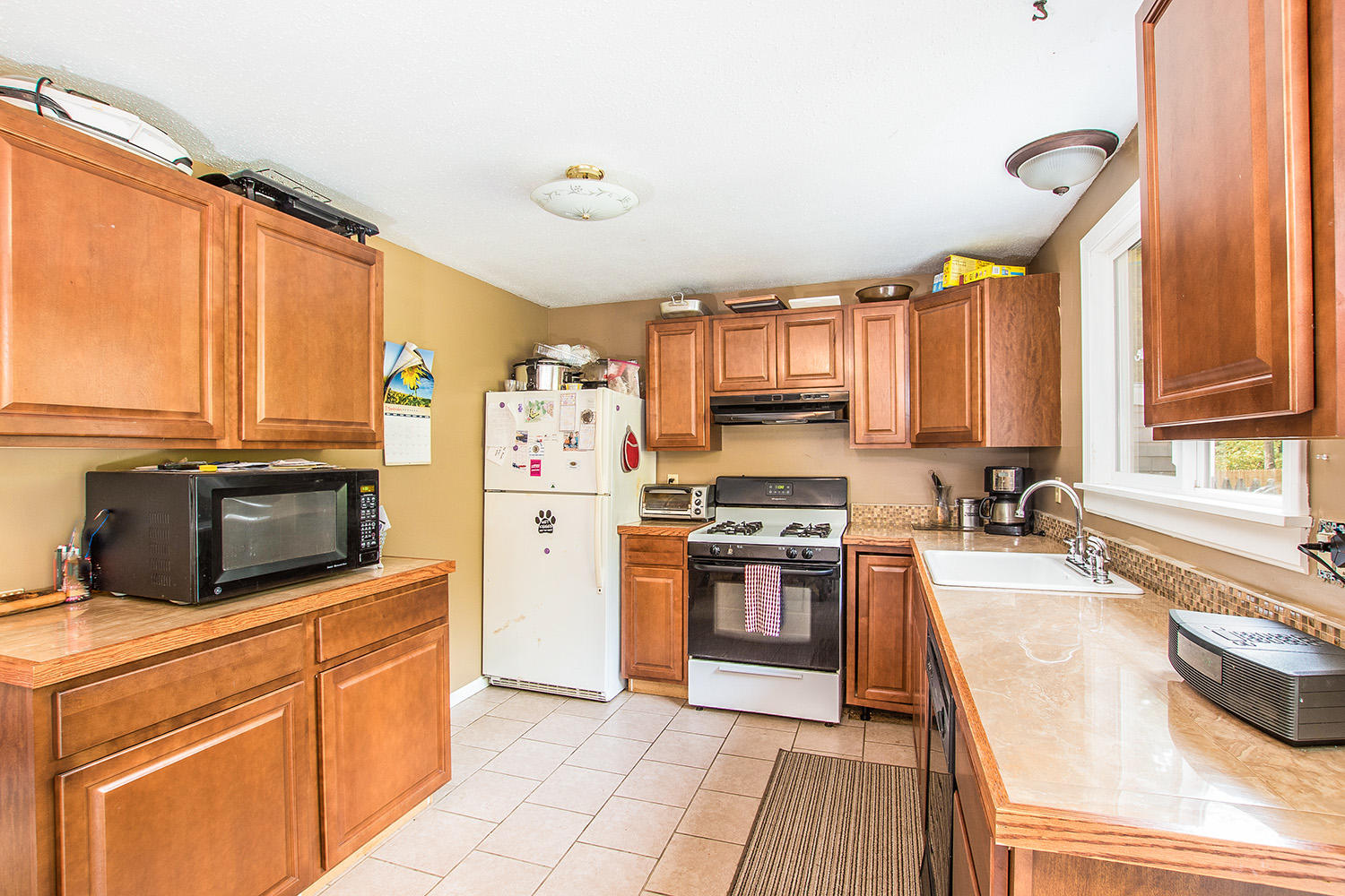 58 Ensign Road Centerville, MA 02632 - Photo 6 of 12 a kitchen with granite countertop a stove top oven a sink dishwasher and a refrigerator with wooden cabinets
