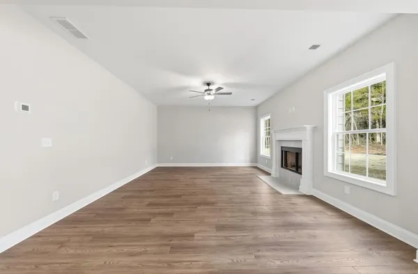 an empty room with wooden floor fireplace and windows