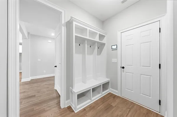 a view of an empty room with wooden floor and a bathroom