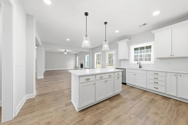 a large kitchen with kitchen island white cabinets and stainless steel appliances