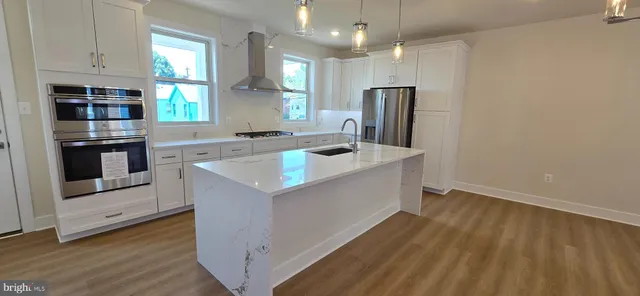 a kitchen that has a sink stainless steel appliances counter space and wooden floor