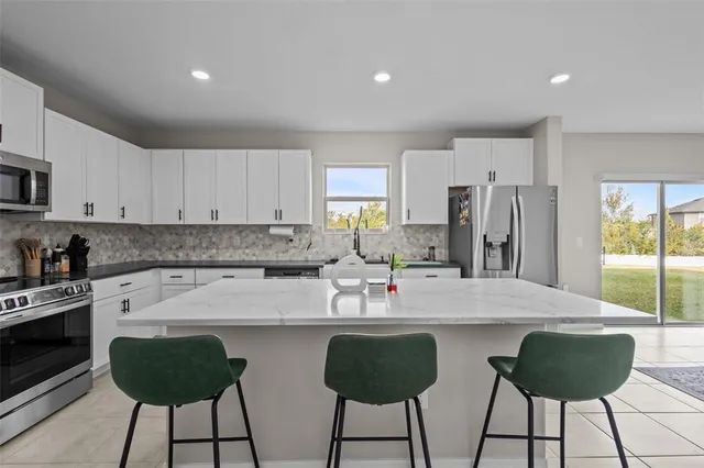 a kitchen with stainless steel appliances granite countertop a stove a sink a refrigerator and a refrigerator with wooden floor