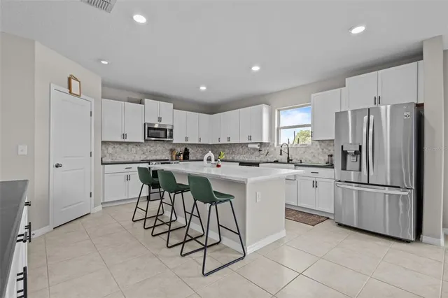 a kitchen with stainless steel appliances granite countertop a refrigerator and white cabinets