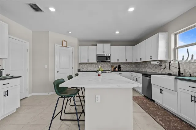 a kitchen with kitchen island a stove a sink a refrigerator and cabinets
