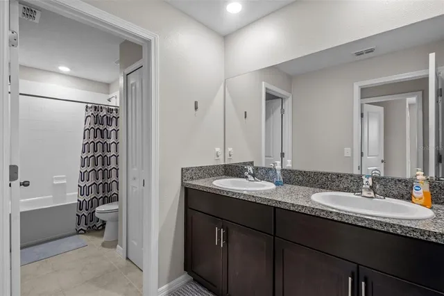 a bathroom with a granite countertop sink a mirror a vanity and a bathtub