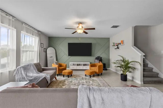 a living room with furniture flowerpot and a flat screen tv