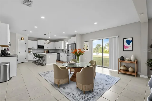 a kitchen with stainless steel appliances granite countertop a sink dishwasher a refrigerator and white cabinets with wooden floor