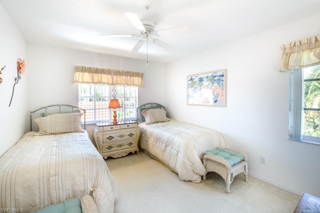448 Gabriel Circle, Unit 3302 Naples, FL 34104 - Photo 16 of 32 a large bed sitting in a bedroom next to a window with a chandelier