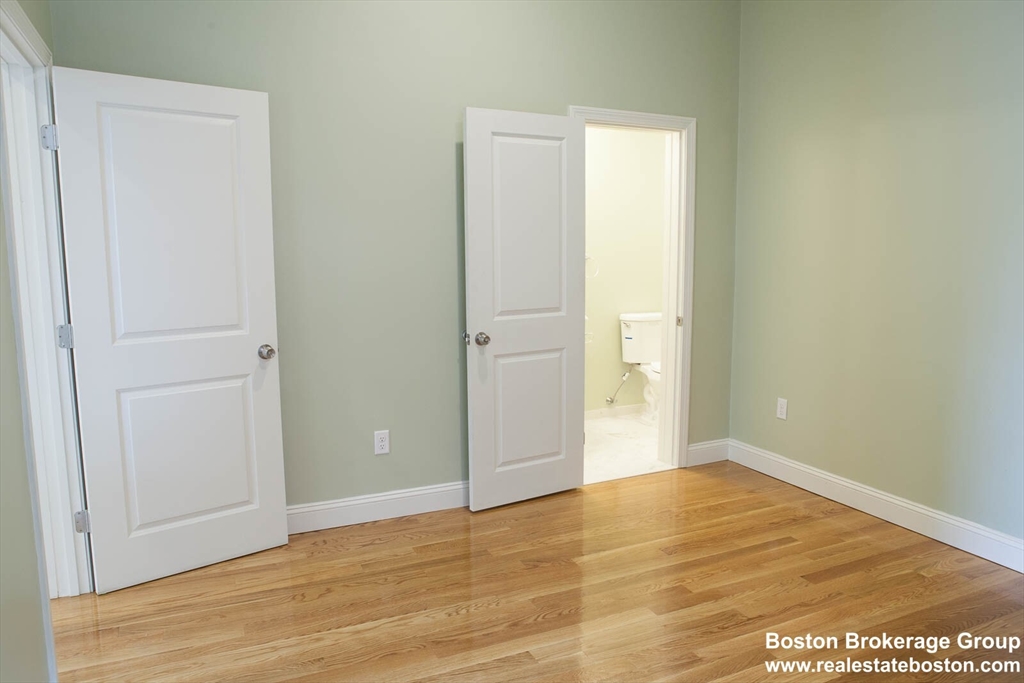 409 Dudley Street, Unit 1 Boston, MA 02119 - Photo 2 of 6 an empty room with wooden floor and windows