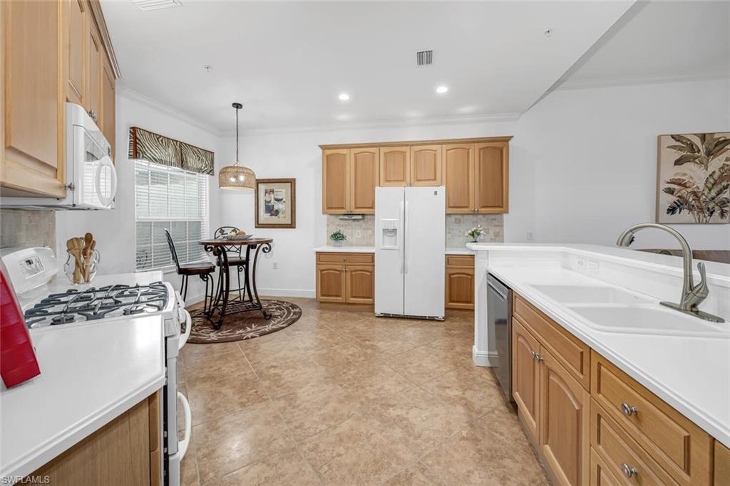 9243 Tesoro Lane, Unit 103 Naples, FL 34114 - Photo 7 of 18 a kitchen with refrigerator and chairs