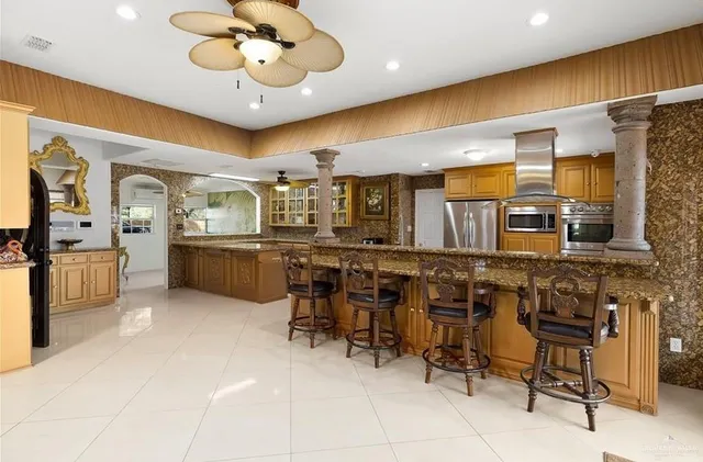 a kitchen with stainless steel appliances kitchen island granite countertop a table chairs sink and cabinets
