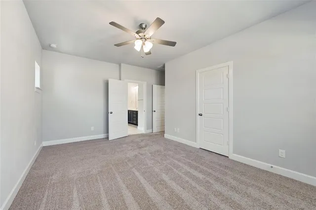 a view of an empty room with chandelier fan