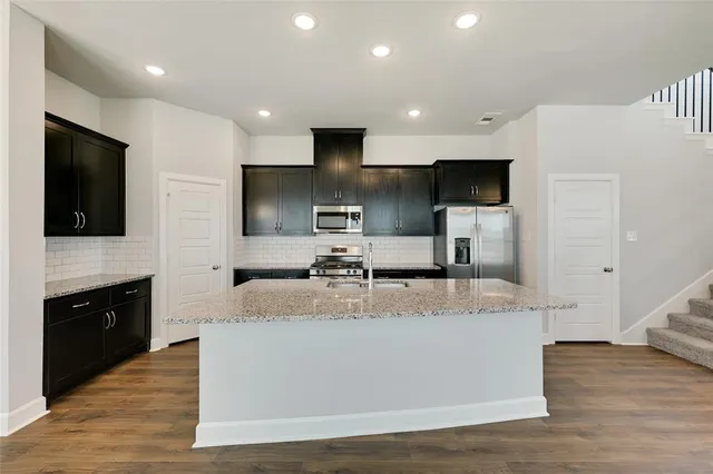 a large kitchen with stainless steel appliances granite countertop a large counter top a stove and a sink