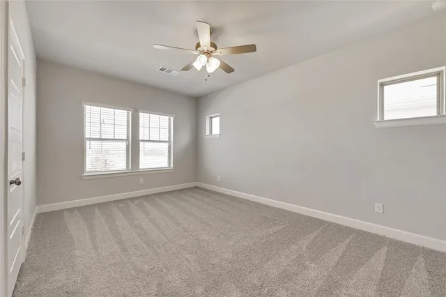 an empty room with chandelier fan and windows