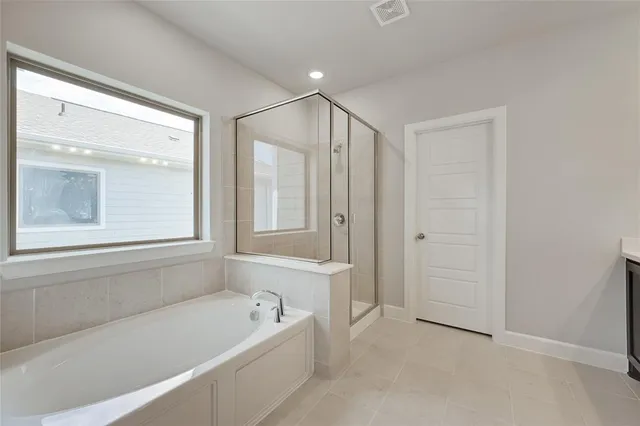 a bathroom with a bathtub a shower a sink and a window