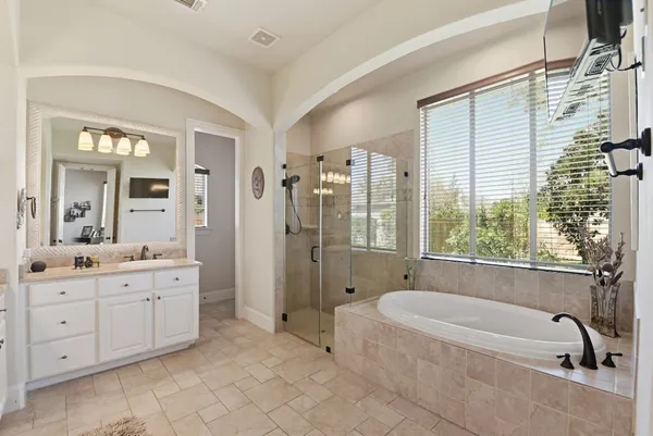 a bathroom with a granite countertop tub a double vanity sink a large mirror and a bathtub