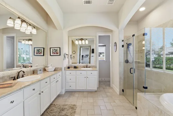 a spacious bathroom with double vanity a mirror a shower and vanity