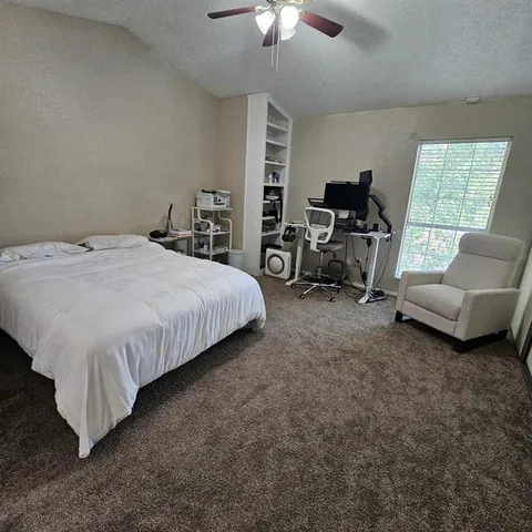 a spacious bedroom with a bed a couch and a chandelier