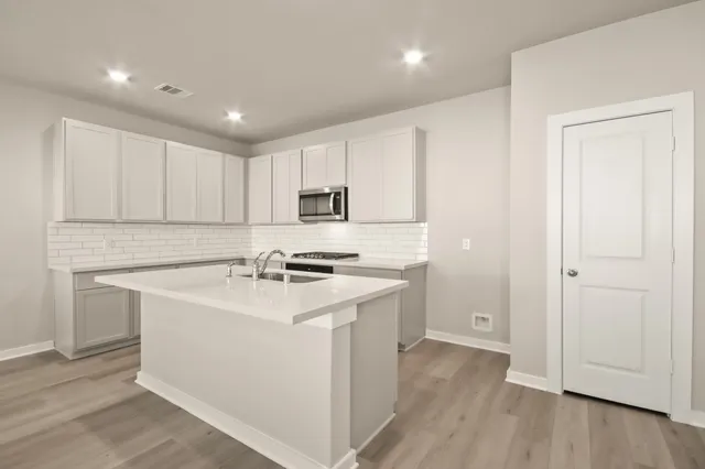 a kitchen with a sink a stove a refrigerator and white cabinets