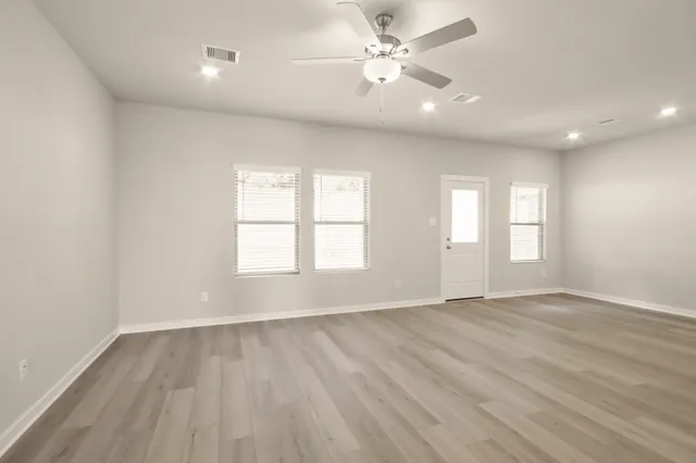 an empty room with wooden floor and windows