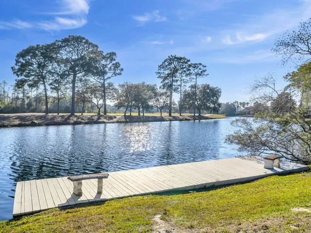 a view of a lake with a yard and trees in the background