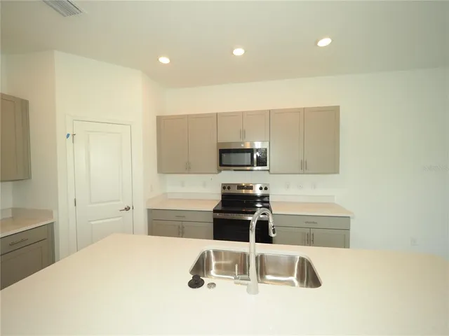 a kitchen with granite countertop a sink stainless steel appliances and white cabinets