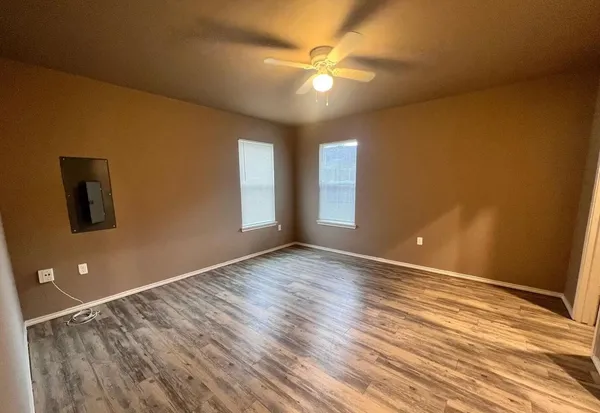 a view of an empty room with window and wooden floor