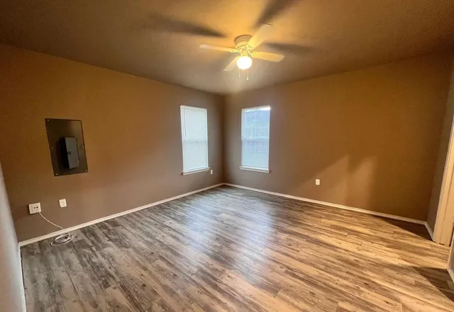 a view of an empty room with window and wooden floor