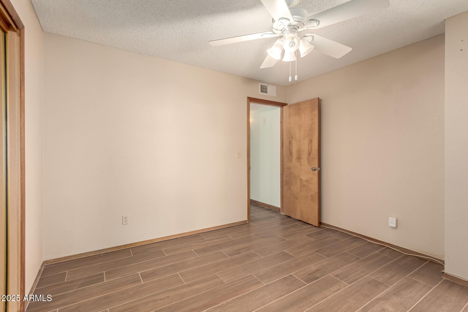 542 South Higley Road, Unit 3 Mesa, AZ 85206 - Photo 16 of 33 an empty room with a chandelier fan and wooden floor