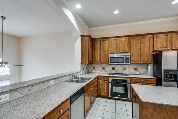 a kitchen with stainless steel appliances granite countertop a sink stove microwave and refrigerator