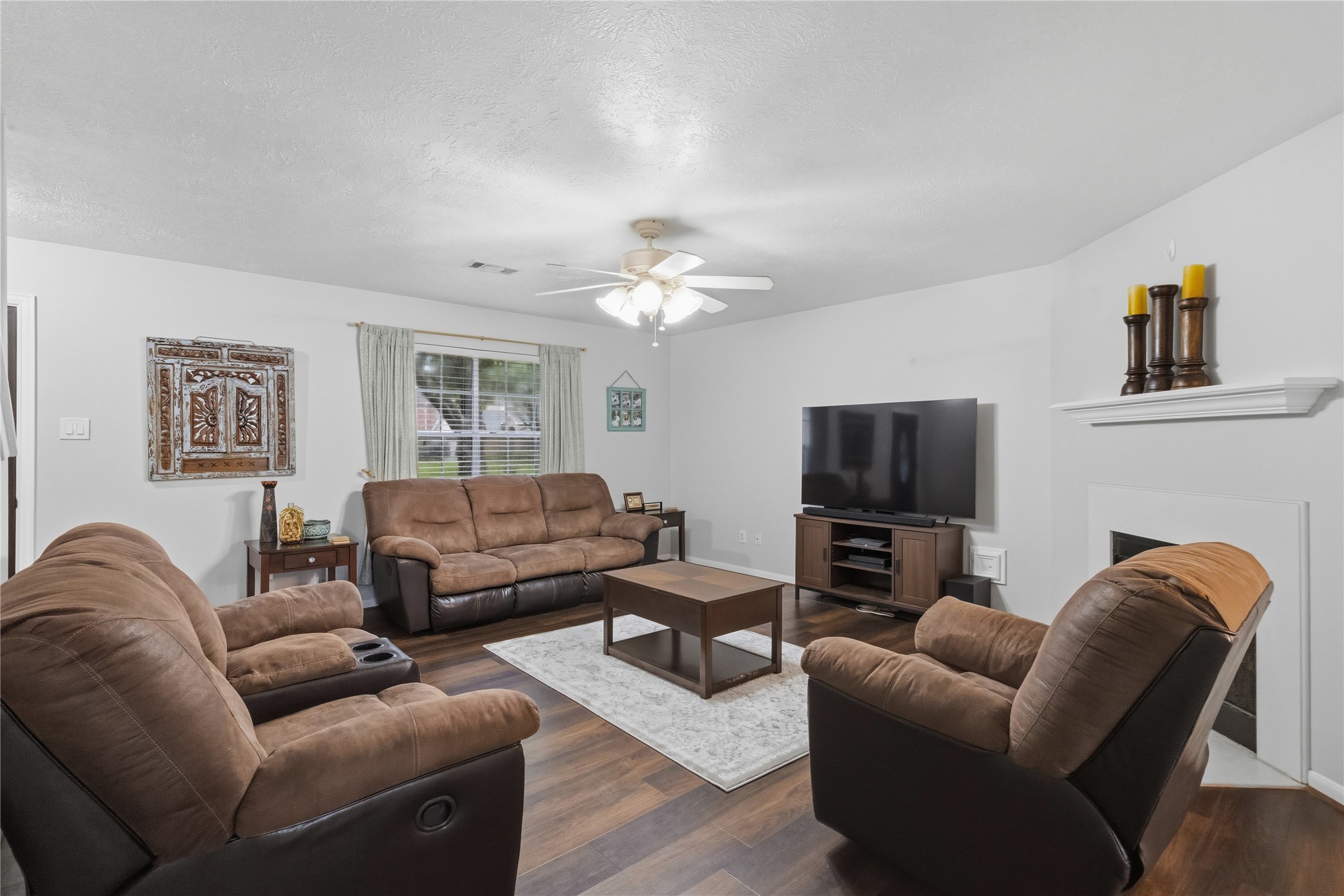 2703 Hidden Spring Vale Drive Spring, TX 77386 - Photo 3 of 29 The living room features a cozy ambiance with a warm fireplace as the focal point. A large window that allows natural light to flood the space, offering a view of the front yard and creating an inviting atmosphere.