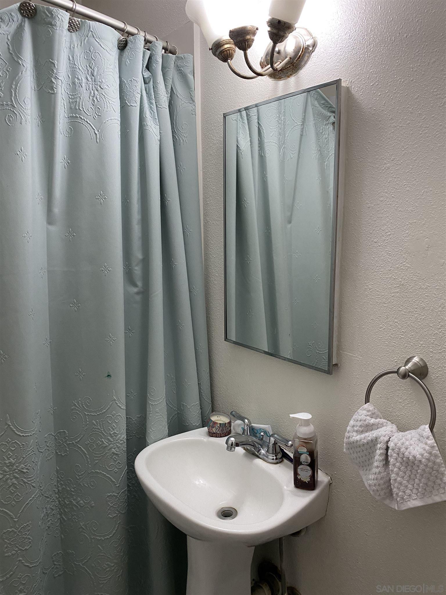 1141 Sumner Avenue El Cajon, CA 92021 - Photo 22 of 32 a bathroom with a sink a mirror and a shower curtain