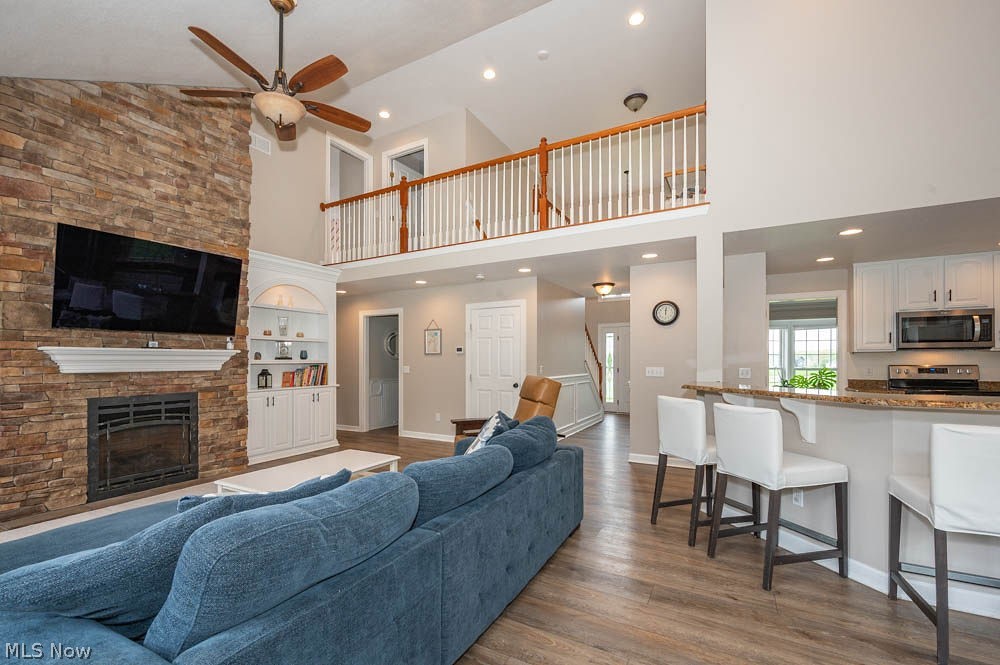 6787 South Palmyra Road Canfield, OH 44406 - Photo 10 of 30 Two-story living area featuring a stacked stone fireplace with a white mantel, wood-finish flooring, and a second-story open-concept landing with a wood railing