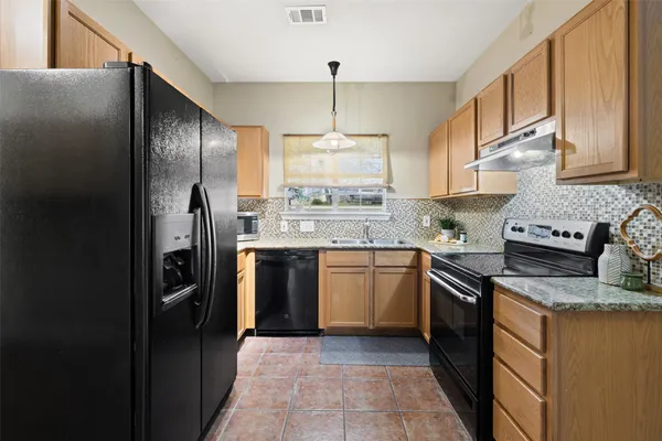 a kitchen with stainless steel appliances granite countertop a refrigerator a sink dishwasher a stove with wooden cabinets and floor