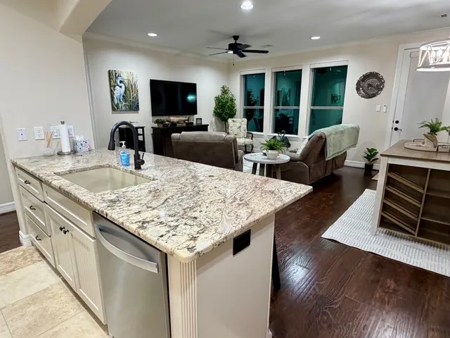 a living room with stainless steel appliances granite countertop a kitchen island a stove and a sink