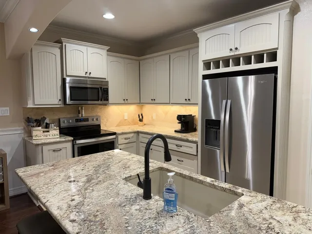 a kitchen with stainless steel appliances granite countertop a refrigerator a stove and a sink