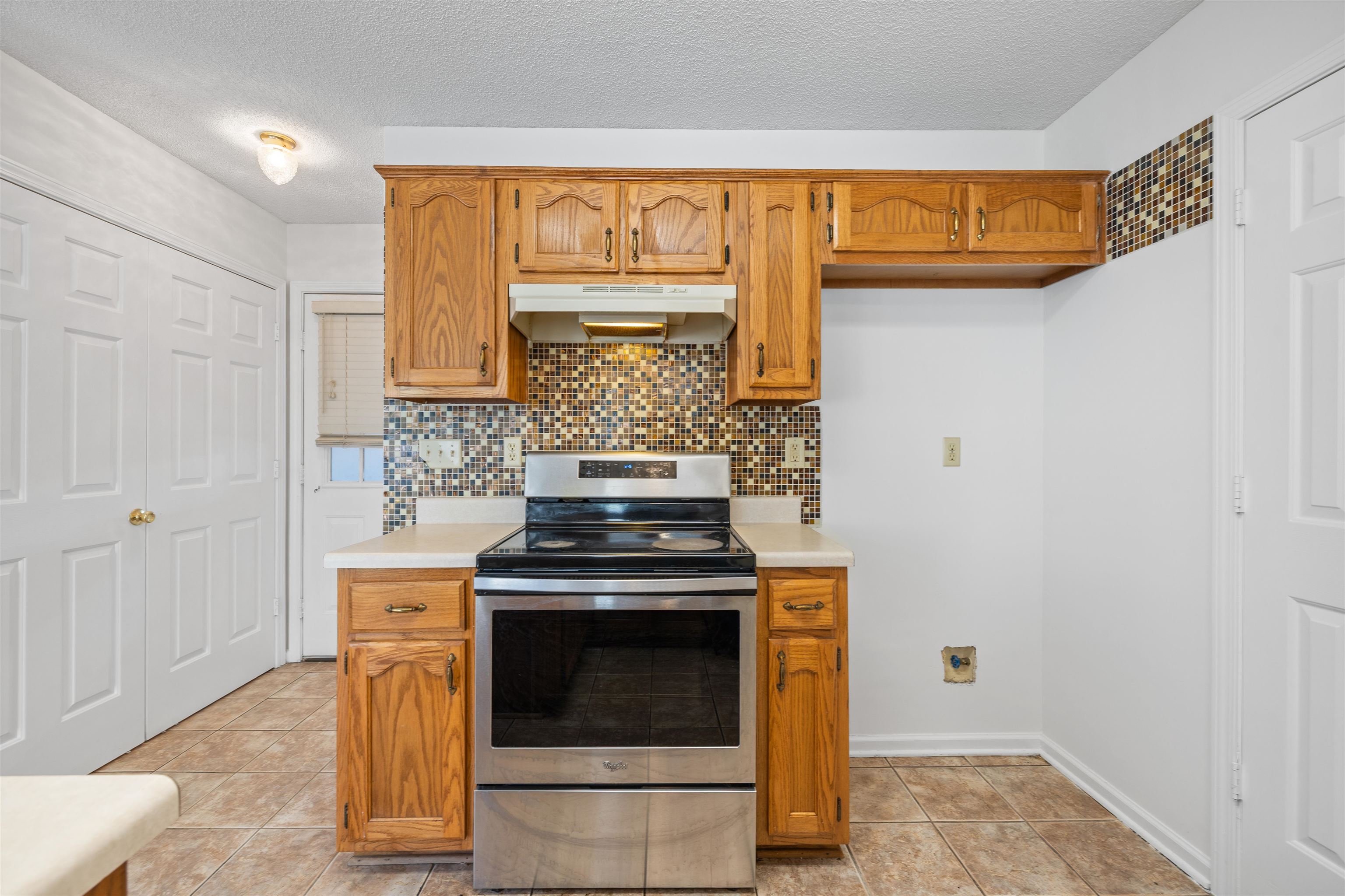 7361 Appling Ridge Drive Cordova, TN 38018 - Photo 18 of 31 Kitchen featuring electric range, light countertops, wood finish cabinets, backsplash, and light tile patterned flooring