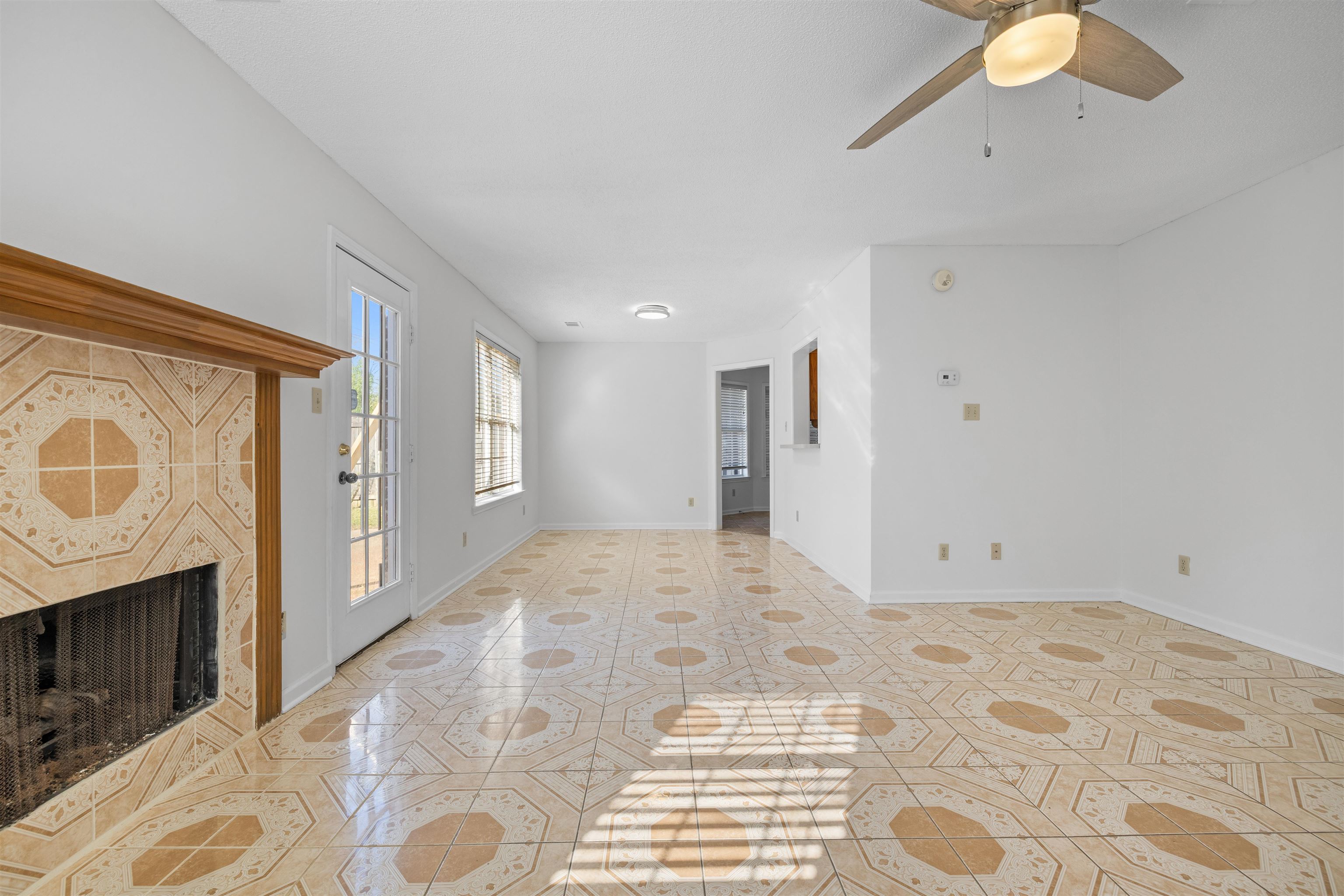 7361 Appling Ridge Drive Cordova, TN 38018 - Photo 5 of 31 Unfurnished living room featuring a tiled fireplace, a ceiling fan, and light tile patterned floors