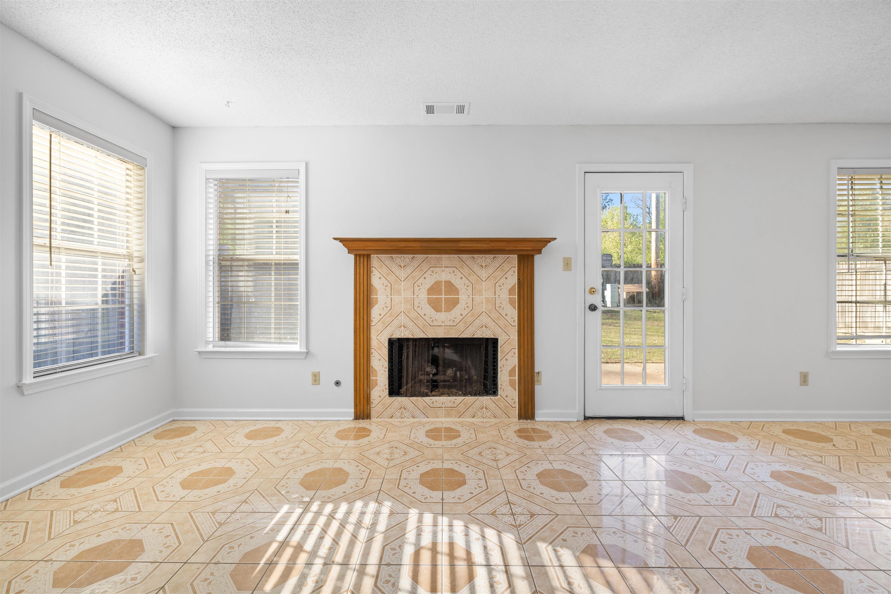 7361 Appling Ridge Drive Cordova, TN 38018 - Photo 6 of 31 Unfurnished living room featuring a tiled fireplace, plenty of natural light, a textured ceiling, and tile patterned floors