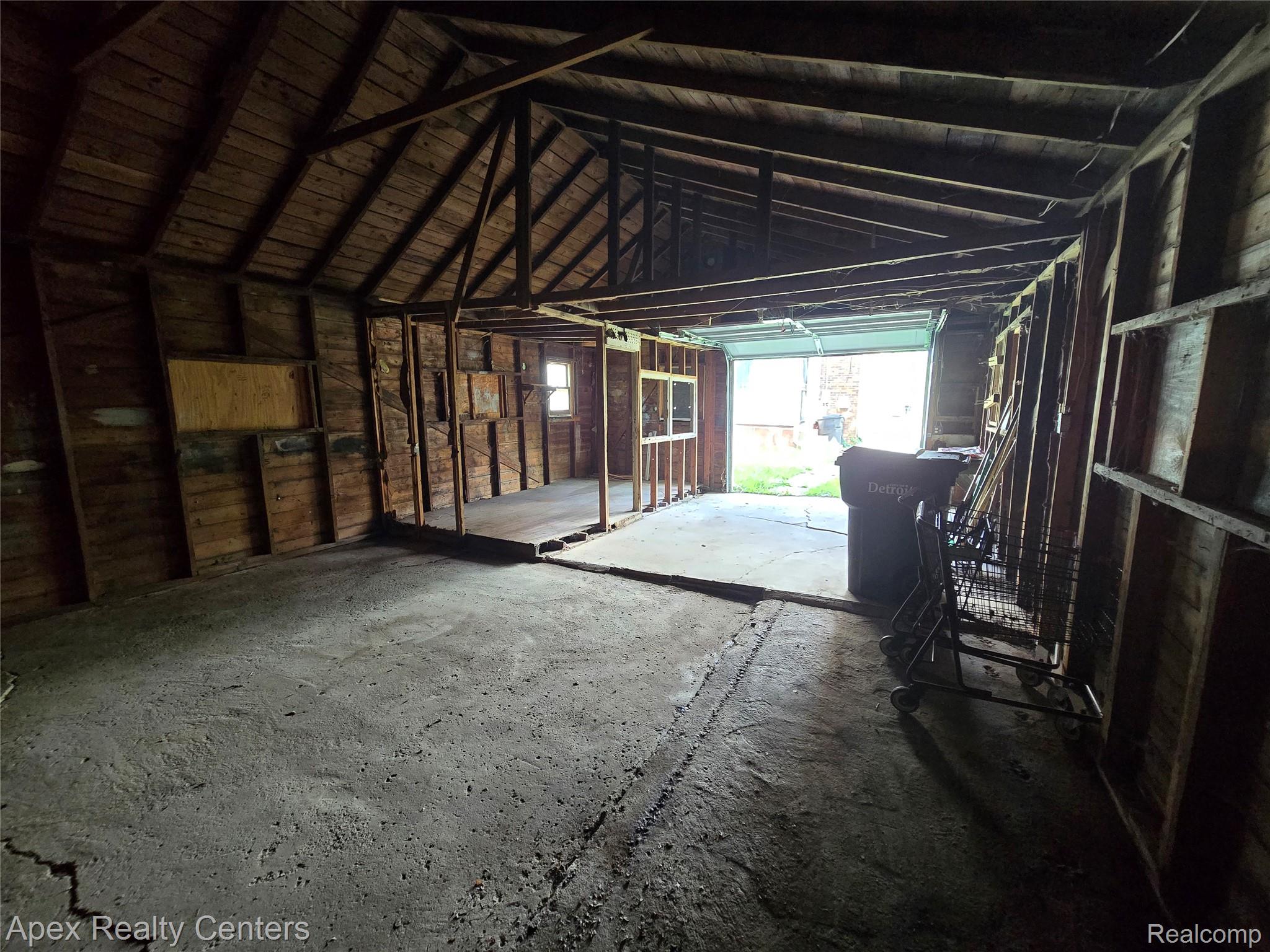 7671-7675 Evergreen Road Detroit, MI 48228 - Photo 18 of 84 Interior garage space featuring a concrete floor, exposed wood framing, and an open garage door