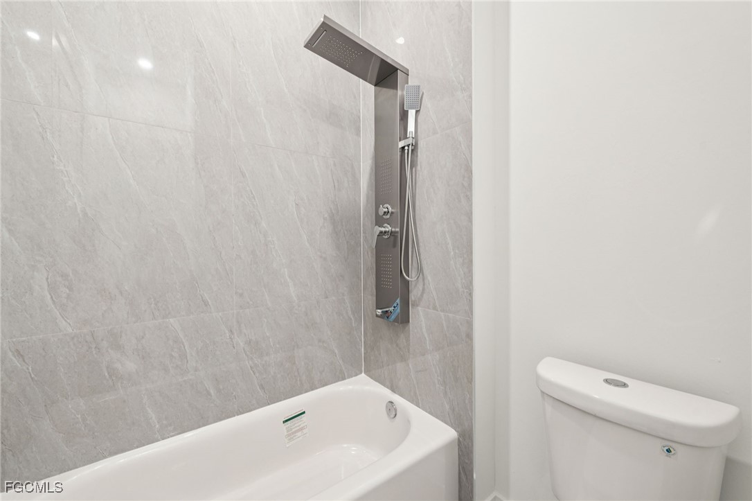 4402 East 19th Street Lehigh Acres, FL 33972 - Photo 20 of 31 a bathroom with a white bath tub and a toilet