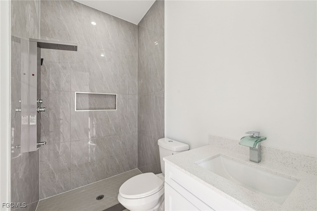 4402 East 19th Street Lehigh Acres, FL 33972 - Photo 25 of 31 a bathroom with a granite countertop sink a toilet and shower