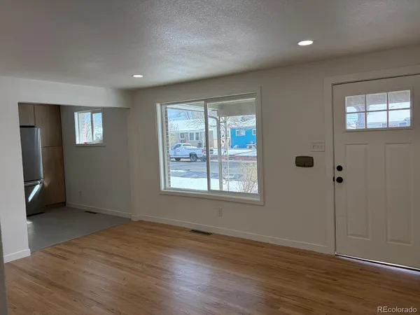 an empty room with wooden floor and windows