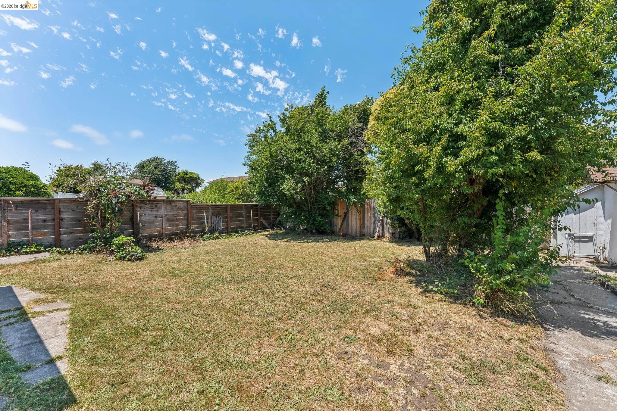 2879 Rheem Avenue Richmond, CA 94804 - Photo 39 of 45 Expansive backyard featuring a grass lawn, mature perimeter trees, and a wooden privacy fence